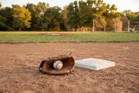 a baseball in a glove beside a base on a ballpark infield