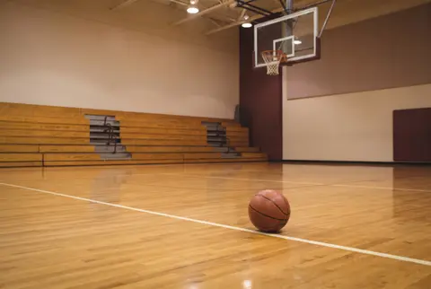 a basketball on the floor of an empty school gym