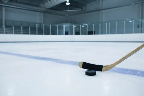 a hockey stick and puck on the ice of an empty rink